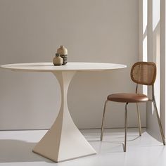 a white table with two chairs and a vase sitting on top of it next to a window