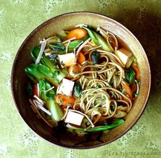 a bowl filled with noodles and vegetables on top of a table