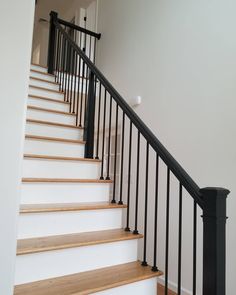 a set of stairs with black railings and wood handrails in a home