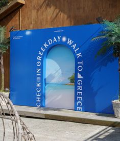 a blue wall with an open door and palm trees next to it in front of a building