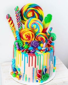 a multicolored cake with candy and lollipops on top