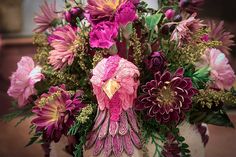 a bunch of flowers that are sitting in the middle of a vase with some kind of bird on it