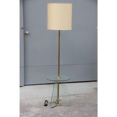 a glass table with a lamp on it in front of a gray wall and door