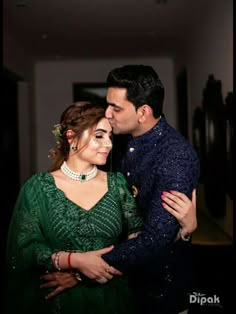 a man and woman embracing each other in front of a wall with lights on it