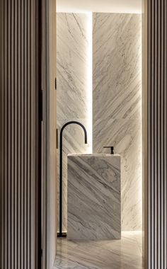 a bathroom with marble walls and flooring next to a black faucet in the middle