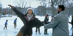 a man and woman standing in the snow with their arms spread out to each other