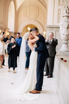 a bride and groom kissing in front of their wedding party at the grand central station