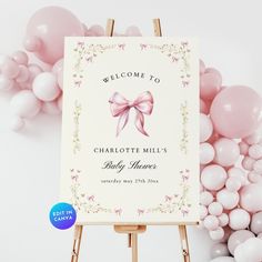 a welcome to charlotte mills baby shower sign on an easel with balloons in the background