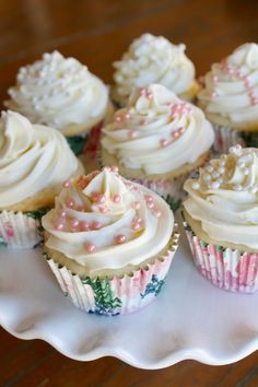 cupcakes with white frosting and pink sprinkles on a plate