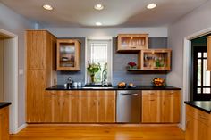 a kitchen with wooden cabinets and black counter tops, along with wood flooring that matches the walls