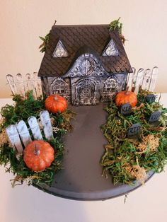 a halloween decoration with fake pumpkins and greenery in front of a small house