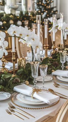 the table is set with white flowers and gold place settings