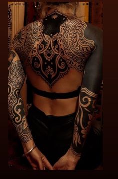 the back of a woman's body with tattoos on her chest and arms,