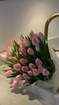 a bouquet of pink tulips sitting on top of a counter next to a sink