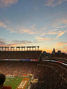 a football stadium filled with lots of people watching the sun go down on it's field