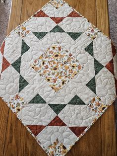 a quilted table topper sitting on the floor in front of a wood floor