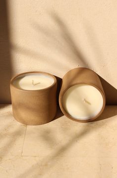 two candles sitting next to each other on a tile floor