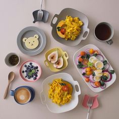 an assortment of breakfast foods are arranged on a table with utensils and cups