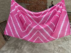 a pink and white towel hanging on a clothes line in front of a brick wall