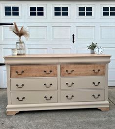 an old dresser has been painted white and is in front of a garage with a clock