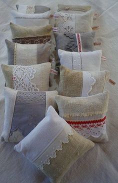 several pillows are arranged in rows on a bed with white linens and crochet lace