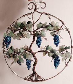 a wire tree with blue grapes hanging from it's center and leaves on the branches