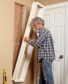 a man standing in front of a white door with a ladder on it's side