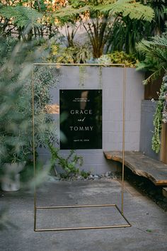 a black and white sign sitting on top of a wooden bench in front of trees