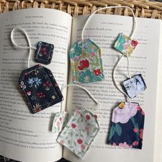 an open book with some small pieces of fabric hanging from it's sides and on the pages