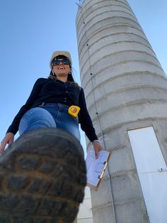 a woman sitting on top of a cement structure next to a tall building with a sky background