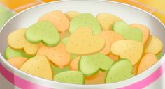 a bowl filled with heart shaped cookies sitting on top of a pink and white table