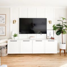 a large flat screen tv mounted to the side of a white wall in a living room