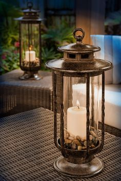 a lit candle sitting on top of a table next to some rocks and candles in a glass container