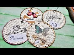 four tags with words and butterflies on them sitting on top of a green table cloth