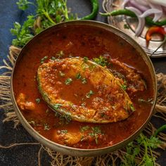 two pieces of meat in a red sauce with garnishes on the side