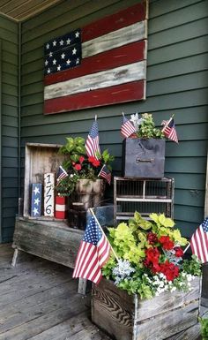 an american flag is on the porch next to some flowers and other patriotic decorations,