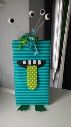 a paper bag that has been decorated with googly eyes and a green frog's nose