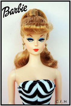 a barbie doll with blonde hair wearing a black and white striped strapless dress on display