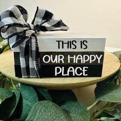 this is our happy place gift wrapped in black and white ribbon on a cake stand