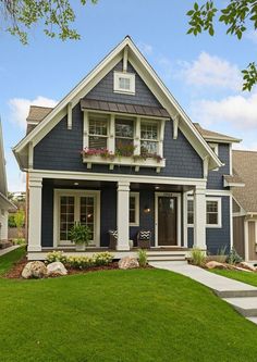 a house with blue siding and white trim on the front door, grass lawn and steps leading up to it