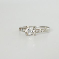 a white gold ring with diamonds on the sides and a center stone in the middle