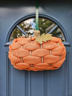 an orange burlock hanging on a blue door with a green ribbon around it