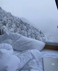 an apple laptop computer sitting on top of a bed covered in white sheets and pillows