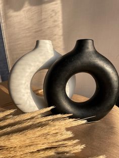 two black and white vases sitting on top of a table