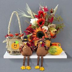 two scarecrows are sitting on a shelf with fall decorations