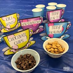 there are many cups and bowls with chocolate chips in them on the blue table cloth