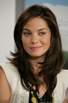 a close up of a person sitting at a table with a glass in front of her