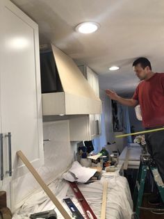 a man standing on a ladder in a kitchen