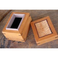 two small wooden boxes sitting on top of a wooden table next to an empty box