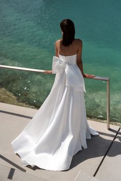 a woman in a white dress looking out over the water